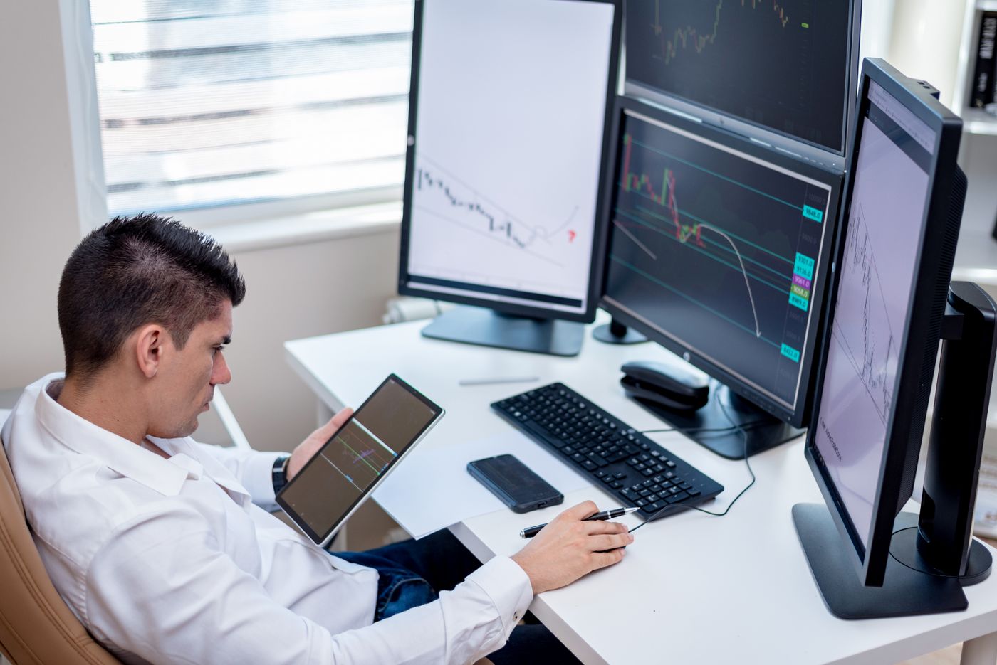A systems analyst working across several monitors and a tablet