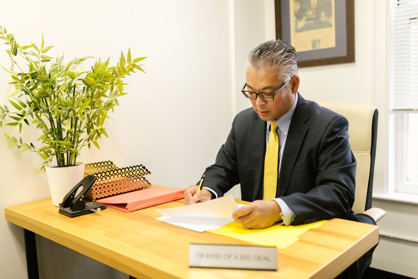 A finance manager signing documents at an office desk
