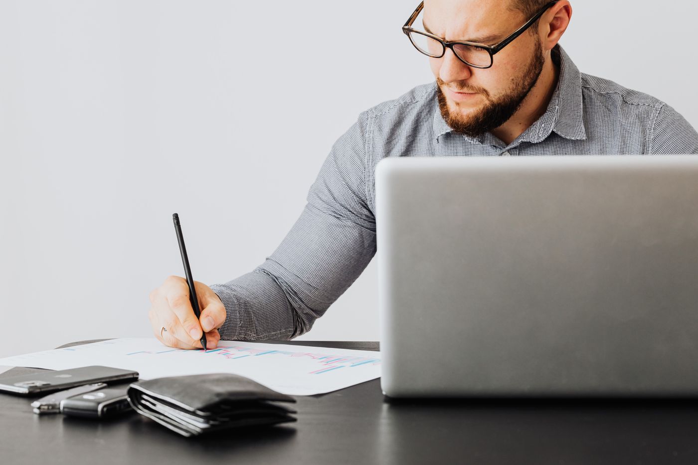 An accountant writing notes beside a laptop