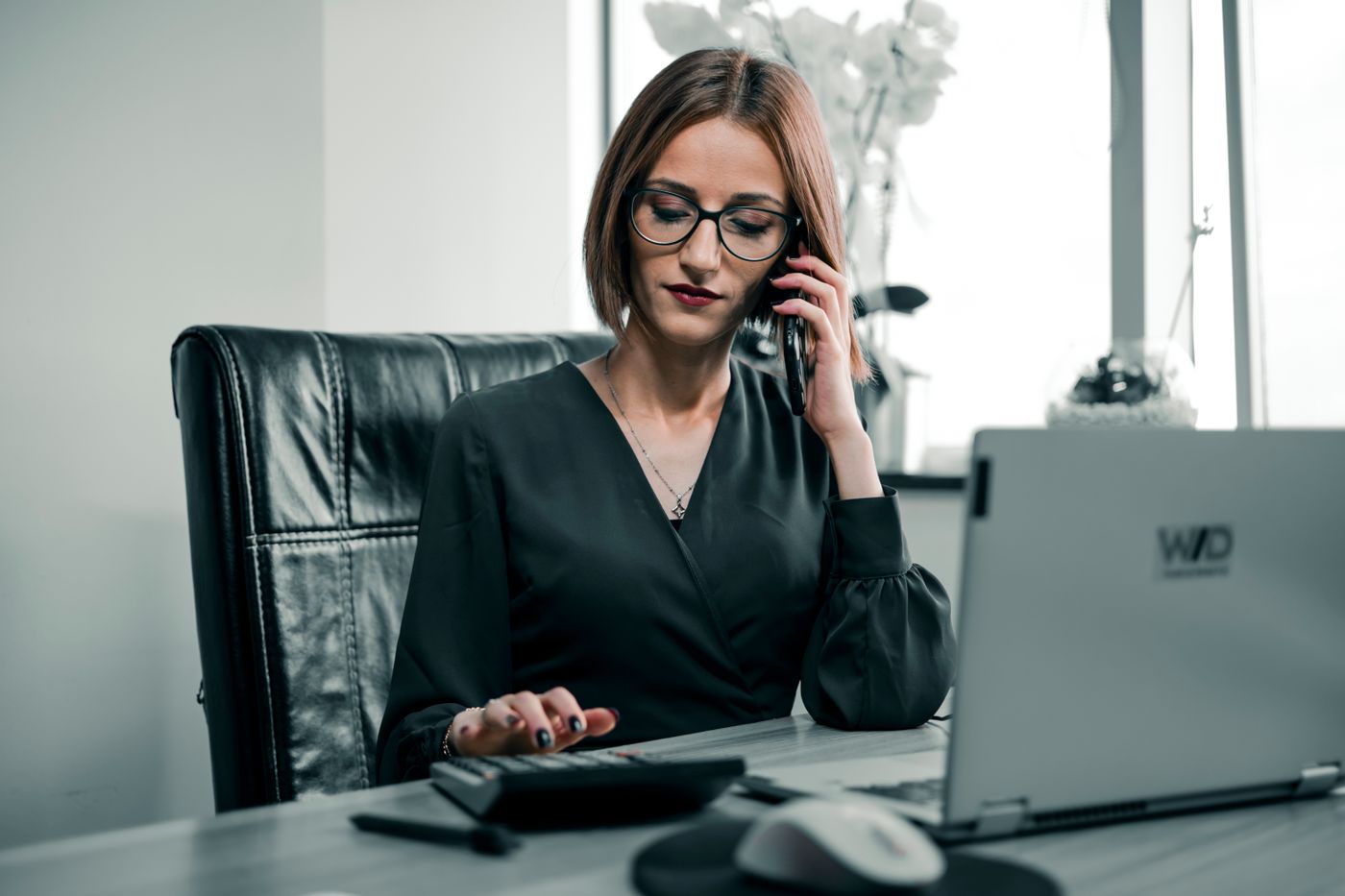 An office manager on a call at a desk with a calculator