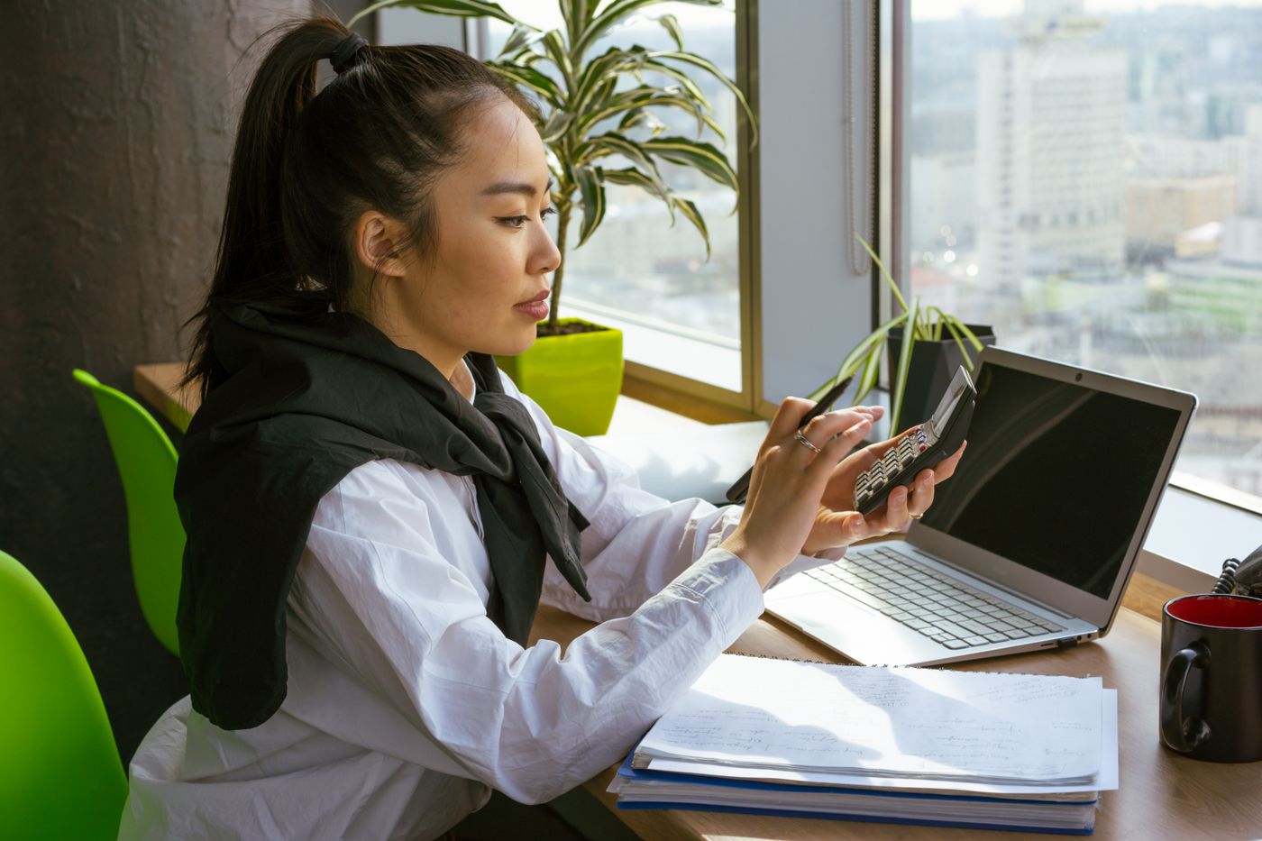 A finance officer working through figures with a calculator and a laptop